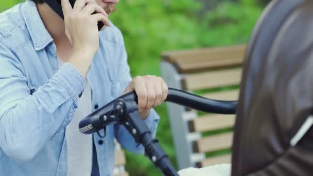 Inexperienced father talking phone swinging crying baby stroller, asking advice — Stock Video