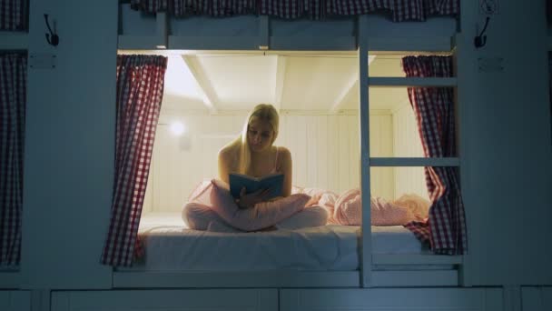 Mujer en ropa interior de noche libro de lectura antes de dormir en la acogedora habitación del albergue — Vídeos de Stock