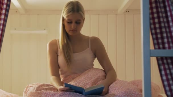 穿着睡衣的女人读完了书，就睡在舒适的旅馆房间里 — 图库视频影像