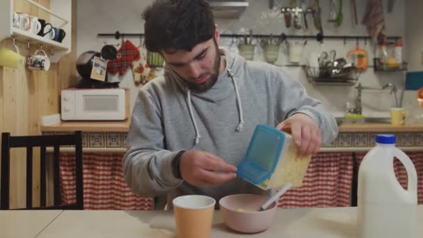 Genç bir adam mutfakta kahvaltı yapıyor. İnsan mısır gevreği yer. — Stok video