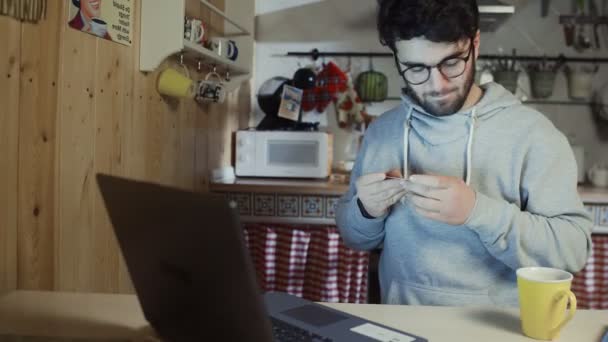 Mladý muž drží svou kreditní kartu o tom, aby se on-line nákup na notebooku — Stock video