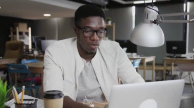 Yorgun Afrikalı iş adamı defteri kapatıyor ve arkasına yaslanıyor