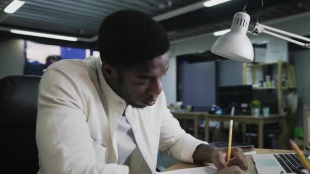 Tired African American businessman working at desk throwing out paper, camera sliding — Stock Video