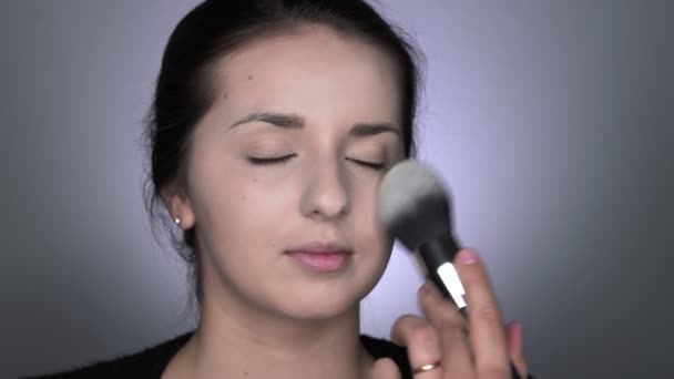 Proces van professionele make-up voor mooie en prachtige vrouw zitten in de Studio. Make-up Kunstenaar brengt poeder met een grote borstel — Stockvideo