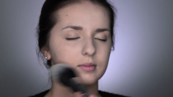 Proces profesionálního make-upu pro krásnou a nádhernou ženu sedící ve studiu. Make-up Artist aplikuje prášek s velkým štětcem — Stock video