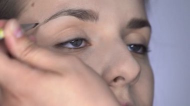 Stüdyoda oturan güzel ve muhteşem kadın için profesyonel makyaj süreci. Makyaj sanatçısı kaşları