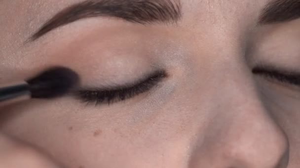 Process of Professional Makeup for beautiful and gorgeous woman sitting at the Studio. Make up Artist applies blush with brush on eyelid — Stock Video