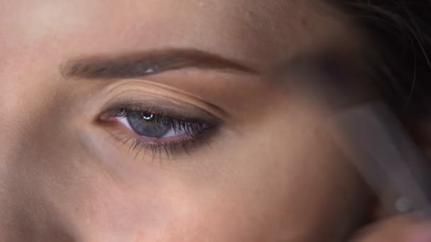 Macro de maquillaje profesional para mujer hermosa y hermosa sentada en el estudio. Maquillaje Artista aplica rubor con cepillo en el párpado — Vídeos de Stock