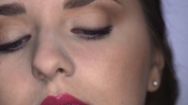 Stüdyoda oturan güzel ve göz kamaştırıcı kadın için Profesyonel Makyaj Süreci 'ni kapat. Makyaj sanatçısı, maskarayı modele uygular