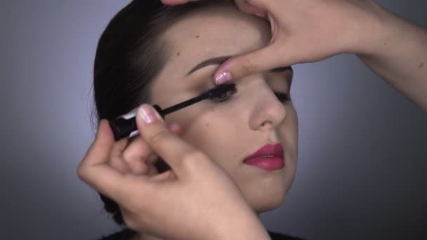 Proces profesionálního make-upu pro krásnou a nádhernou ženu sedící ve studiu. Make-up Artist aplikuje řasenku na model — Stock video