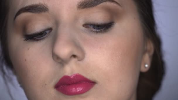 Detailní záběr procesu profesionální make-up pro krásnou a nádhernou ženu sedící ve studiu. Make-up Artist aplikuje řasenku na model — Stock video