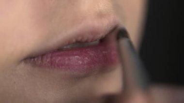 Güzellik stüdyosunda genç bir kadın için profesyonel makyaj yapıyor. Makyaj sanatçısı dudaklara ruj sürer