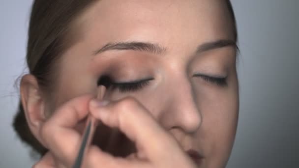 Makeup artist making professional make-up for young woman in beauty studio. Make up Artist uses brush to applies shadow on eyelid — Stock Video