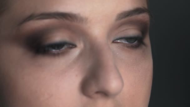 Μακρο πλάνο του Μακιγιάζ καλλιτέχνη κάνοντας επαγγελματική make-up για τη νεαρή γυναίκα στο στούντιο ομορφιάς. Μακιγιάζ Καλλιτέχνης χρησιμοποιεί βούρτσα για να εφαρμόσει σκιά στο βλέφαρο — Αρχείο Βίντεο