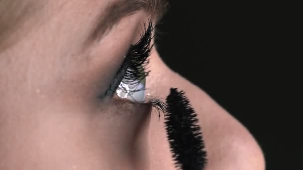 Macro shot of Makeup artist making professional make-up for young woman in beauty studio. Make up Artist uses mascara to make eyelashes — Stock Video