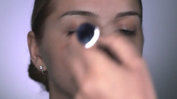 Makijażysta robi profesjonalny makijaż dla młodej kobiety w studiu kosmetycznym. Make up Artist nakłada proszek dużą szczotką — Wideo stockowe