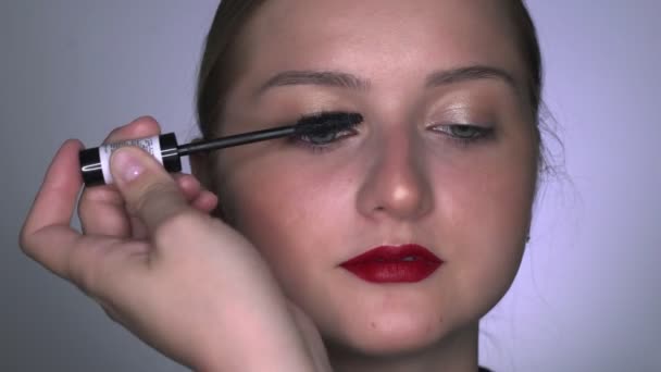 Макияж художник делает профессиональный макияж для молодой женщины в студии красоты. Составитель рисует ресницы тушь для ресниц — стоковое видео