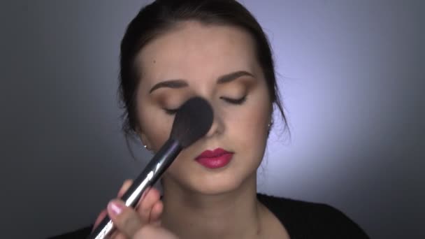 Professionele make-up voor mooie en prachtige vrouw zitten in de Studio. Make-up Kunstenaar brengt poeder met een grote borstel — Stockvideo
