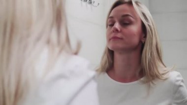 Banyoda aynaya bakan zarif genç bir kadın.