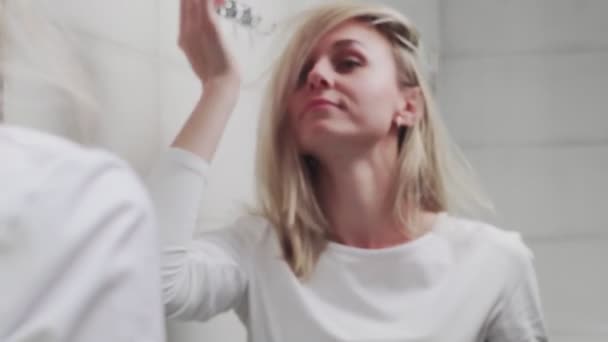 Mooie vrouw kijken naar de spiegel en aanraken van haar gezicht — Stockvideo