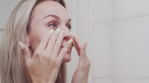 CLose up of Elegant young woman looking at mirror and touching her face in bathroom — Stock Video