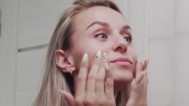 Krem süren ve aynaya bakan kadın doğal güzelliğin ve sağlığın tadını çıkarıyor.