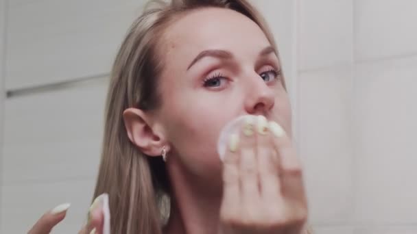 Vrouw die lotion aanbrengt en naar de camera kijkt — Stockvideo