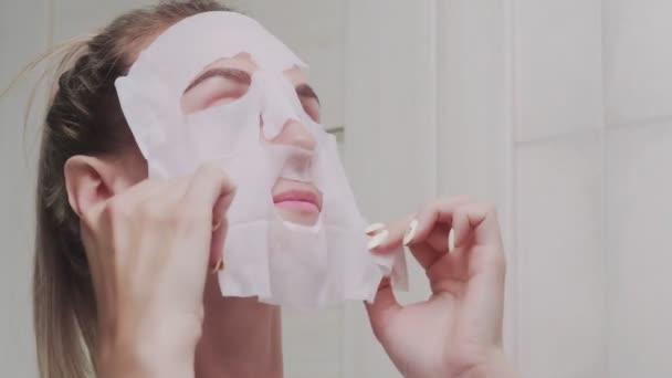 Крупный план женщины, надевающей маску на лицо, смотрящей в зеркало — стоковое видео