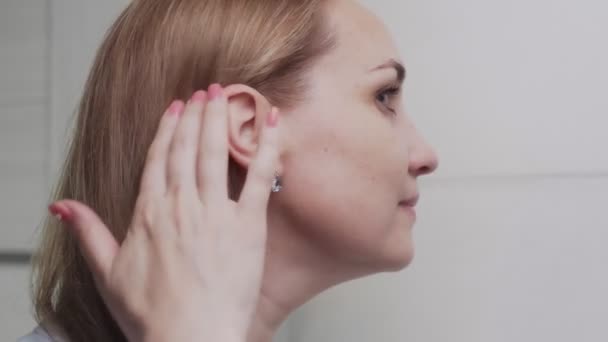 Close-up van elegant jong vrouw kijken naar spiegel en aanraken van haar gezicht in badkamer — Stockvideo