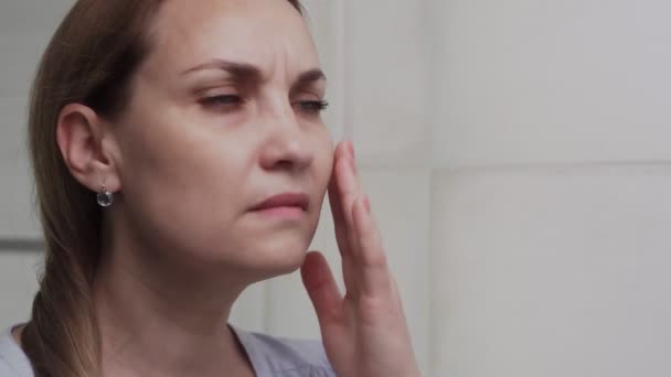 CLose up de femme adulte frustrée regarde son visage dans le miroir de la salle de bain — Video