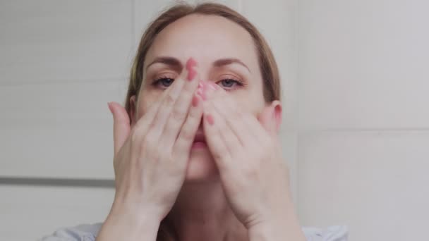 Kvinna som applicerar lotion eller olja och tittar på kameran — Stockvideo