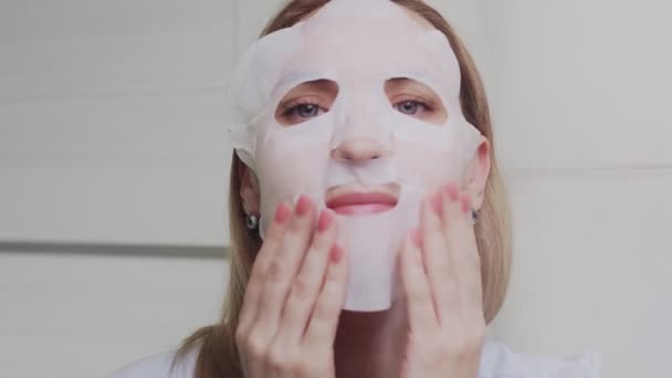 Крупный план взрослой женщины, надевающей маску на лицо и смотрящей в камеру — стоковое видео