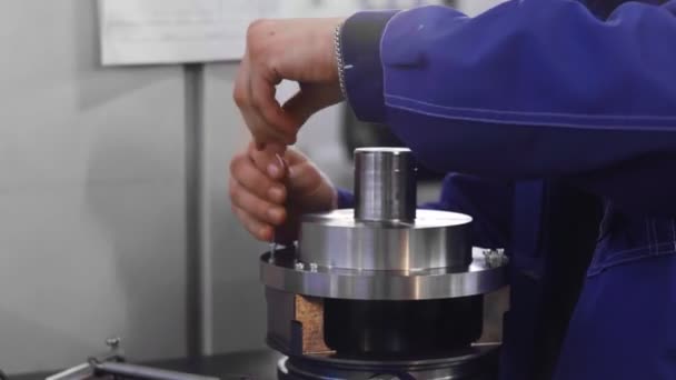 Arbetstagaren skruvar och monterar en mekanism — Stockvideo