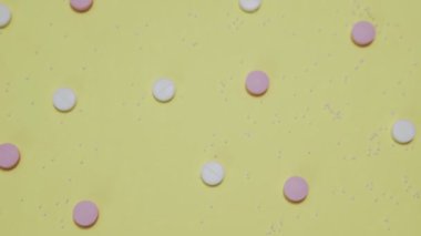 Sarı arka planda pembe ve beyaz haplar.