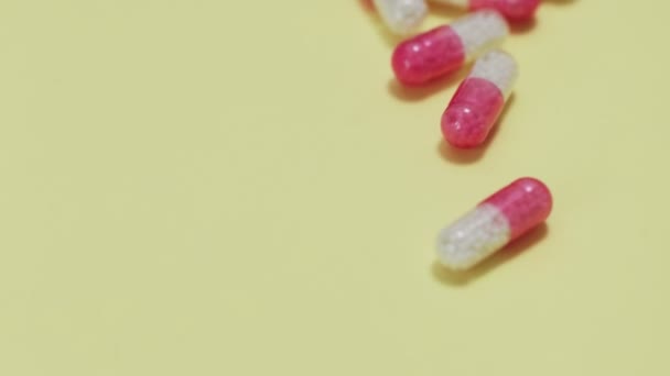 Růžové a bílé pilulky s lahví na žlutém pozadí