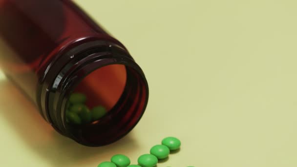Pílulas verdes com garrafa no fundo amarelo — Vídeo de Stock
