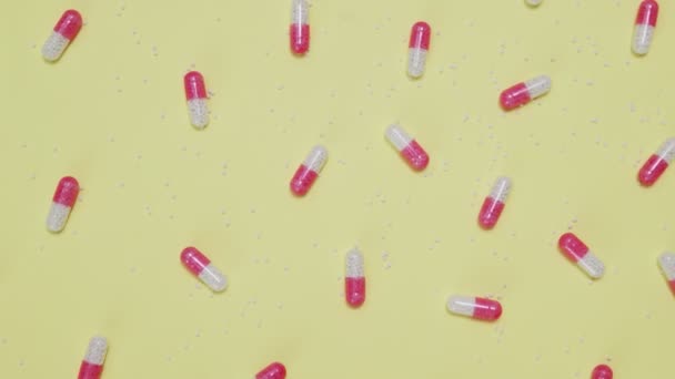 Roze en witte pillen op gele achtergrond — Stockvideo