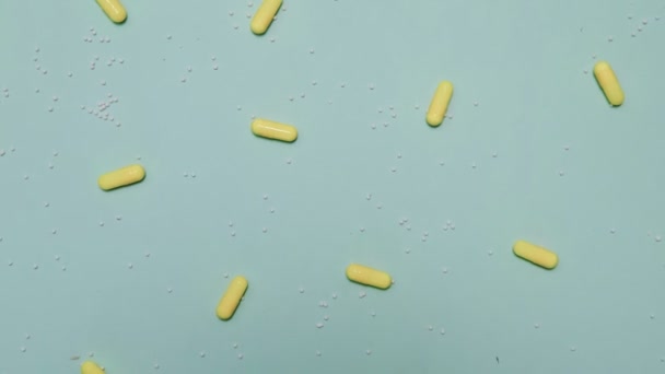Un montón de pastillas amarillas sobre fondo azul — Vídeos de Stock