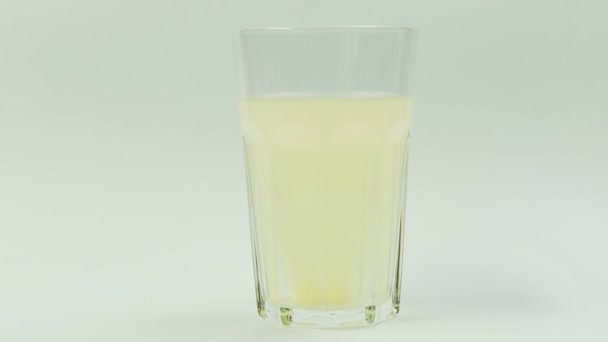 Piller som faller ner i glas med vatten. brusande tablettaspirin. närbild på vit bakgrund — Stockvideo