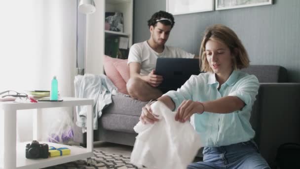 Young couple getting ready for travel, packing clothes and plane tickets in a suitcase — Stock Video