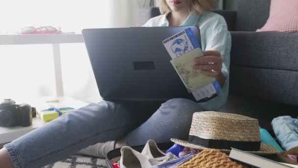 Девушка с билетами на отдых работает на ноутбуке — стоковое видео