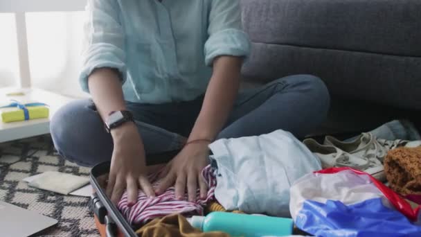 Дівчина акуратно кладе одяг для відпустки у валізу — стокове відео
