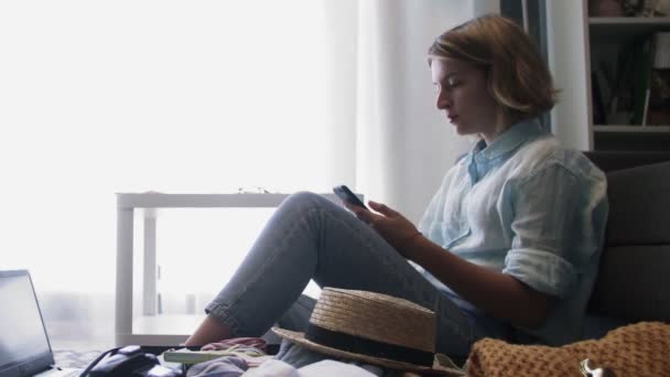 Junge Reisefrau sitzt neben geöffnetem Koffer und telefoniert — Stockvideo