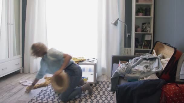 Ung kvinna rusar på ett plan och kastar allt i en resväska — Stockvideo