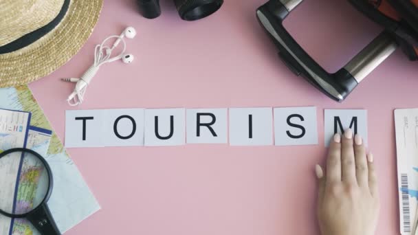 Ovanifrån händer på rosa skrivbord ord TOURISM — Stockvideo