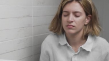 Genç uykulu kadın yüzünü yıkıyor ve bir banyoda havluyla siliyor.