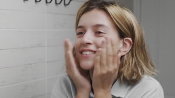 Молодая женщина умывает лицо и вытирает его полотенцем в ванной — стоковое видео