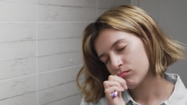 Sleepy woman cleaning tooth with brush in bathroom — Stock Video