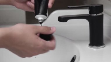 Siyah jeli sıkan adam ya da siyah maskeyi açık avucuna banyoda dururken sıkan adam.