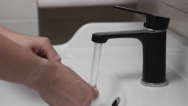 Young man brushing teeth with a tooth brush in bathroom. Close-up of hands cleaning brush after brushing teeth — Stock Video